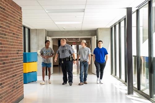 Officer Noles walks with 3 students